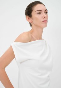 Top bianco off-the-shoulder con design drappeggiato. Realizzato in tessuto morbido, presenta una superficie liscia e dettagli di cucitura minimi.