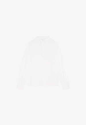 Blouse blanche à manches longues avec un col haut, une patte de boutonnage et des poignets froncés. Tissu doux avec de délicats détails à bords festonnés le long de l'encolure.