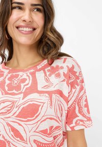 Rot-weißer, blumengemusterter Kurzarm-T-Shirt aus leichtem Stoff mit rundem Halsausschnitt und lockerer Passform.