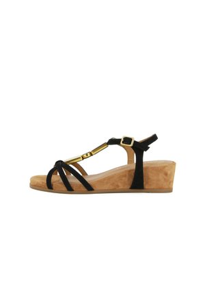 Sandalo con zeppa da donna con suola in pelle scamosciata color beige, cinturini neri, barra decorativa color oro e fibbia regolabile alla caviglia.