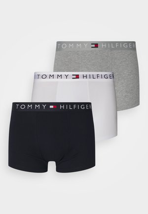 Trois boxers pour hommes en noir, blanc et gris, chacun avec une ceinture marquée Tommy Hilfiger et un logo drapeau.