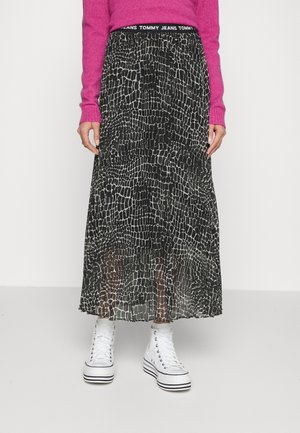 Femme portant une jupe maxi à motif noir et blanc, un pull rose à manches longues et des baskets blanches montantes à semelles compensées.