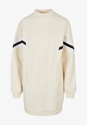 Sudadera color crema con cuello alto, mangas largas y bolsillos laterales. Presenta rayas horizontales en blanco y negro en los hombros.