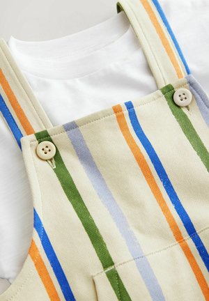 Beige stribede denimoveraller med lodrette striber i grøn, blå, orange og lavendel. Afsluttet med to beige knapper og en hvid t-shirt under.