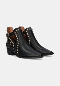 Botas de tobillo de cuero negro con punteras afiladas, tachuelas doradas a lo largo de los lados y un detalle de hebilla en un lado. Textura suave, tacones bajos de bloque.