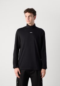 Svart langermet genser med høy hals laget av glatt stoff, med en liten hvit "HUGO" logo på brystet. Minimalistisk design.