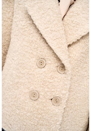 Beige wollen jas met structuur, grote revers en vier bijpassende beige knopen aan de voorkant.