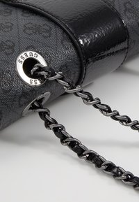 Sort håndtaske i struktureret stof med blanklæderdetaljer, der har en sølv logoøje og en sort kædetras.