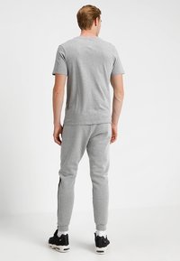 Grå bomull t-shirt och matchande joggers, med en avslappnad passform och sidodetaljer, tillsammans med svarta sneakers och vita strumpor.