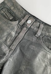 Jean en denim gris métallisé avec fermeture à boutons sur le devant, deux poches et une surface texturée avec un léger éclat.