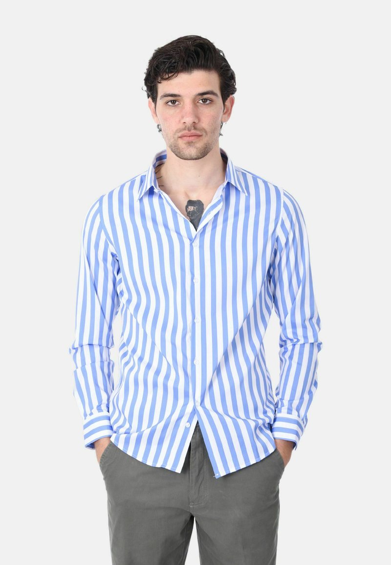 Camicia a righe blu e bianche con bottoni, maniche lunghe, colletto classico e vestibilità sagomata, abbinata a pantaloni grigi.