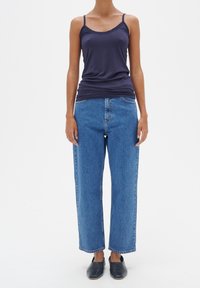 Marinblå linne, blå högmidjade vida jeans, svarta slip-on skor. Slätt material, avslappnad design och standard jeanssöm detaljer.