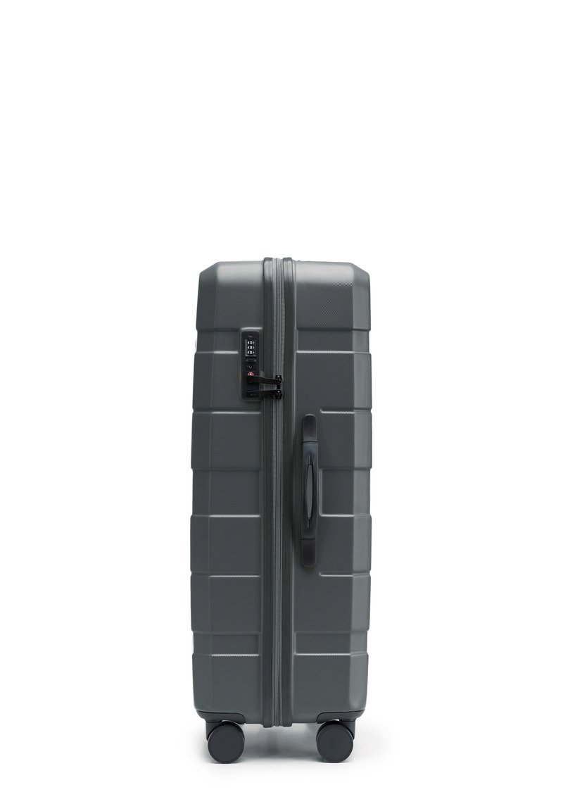Šedý kufr s tvrdým povrchem, se strukturovaným vzhledem, svislými rýhami, kombinovaným zámkem, boční rukojetí a čtyřmi černými kolečky pro snadnou přepravu.