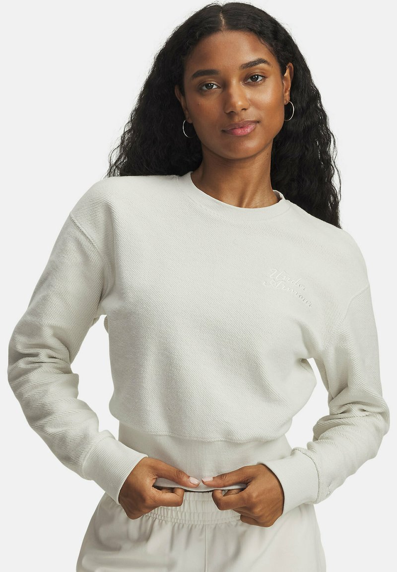 Sweatshirt crème, texturé, avec des poignets et une taille côtelés, arborant un petit détail brodé sur la poitrine. Coupe décontractée et confortable.
