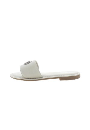 Flad sandal i lys beige syntetisk materiale med en bred rem og en dekorativ metaludsmykning. Fleksibel såledesign.