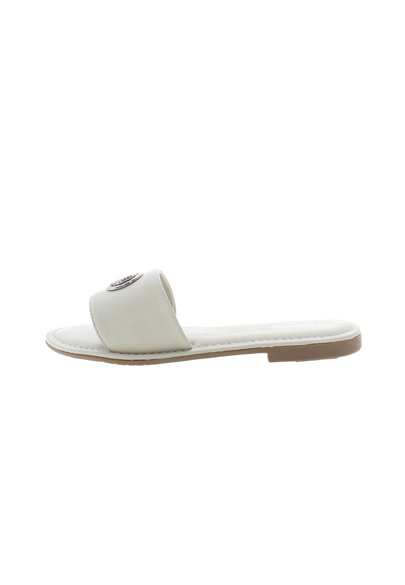 Flat slide sandal in light beige synthetic material, featuring a wide strap with a decorative metallic embellishment. Flexible sole design.