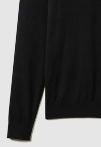 Pull noir en tricot avec des manches longues et des poignets côtelés. Texture douce avec une finition lisse, présentant un design simple et classique.
