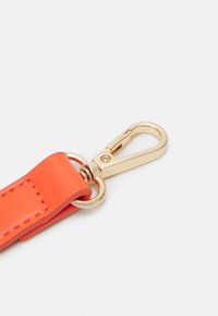 Jasnopomarańczowy pasek z eko skóry z metalowym klipsem w złotym odcieniu, charakteryzujący się gładką fakturą i solidną konstrukcją do zabezpieczania przedmiotów.