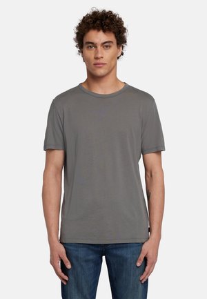 T-shirt gris à manches courtes en tissu doux, avec un col rond et une coupe décontractée. Porté avec un jean en denim bleu.