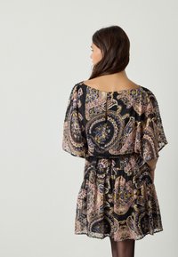 Zwarte jurk met een paisley-patroon in tinten roze, blauw en geel. Losse mouwen, elastische taille en knoopsluiting aan de achterkant.