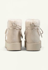 Beige suede ankle boots with faux fur lining, flat platform sole, and rear pull tabs for easy wear. Smooth texture, round toe design.