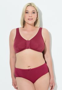 Burgunderfarbener BH mit weichen Cups und breiten Trägern, verziert mit einem mittigen Rüschendetail, kombiniert mit passendem hochgeschnittenem Slip mit Schleifenakzent.