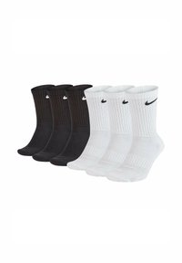 Confezione da quattro paia di calzini Nike: due neri e due bianchi, con texture a coste, lunghezza a metà polpaccio, dotati del logo Nike sul risvolto in colori a contrasto.