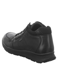 Chaussure en cuir noir avec une forme arrondie, dessus texturé et semelle en caoutchouc. Équipée d'une fermeture éclair et d'un talon renforcé pour un meilleur soutien.