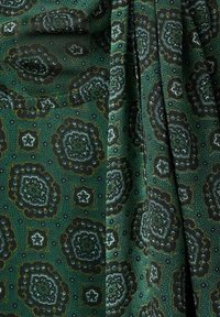 Tela verde estampada con intrincados diseños geométricos y florales en tonos más oscuros. Textura suave con un ligero brillo y caída.