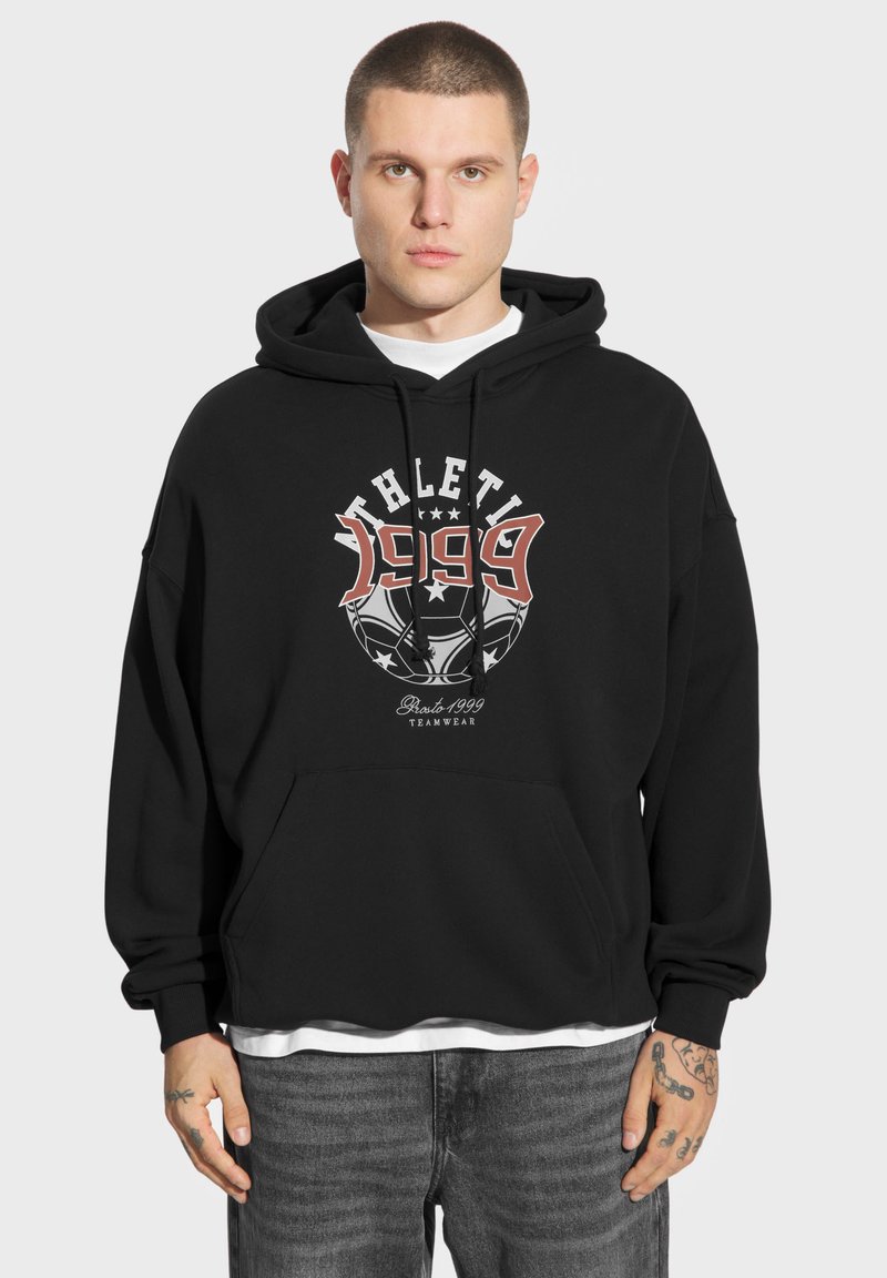 Czarna, oversize bluza z kapturem z grafiką przedstawiającą napis "ATHLETIC" oraz "1999" w białym i czerwonym kolorze. Miękka bawełniana tkanina i przednia kieszeń kangurza.