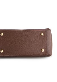 Braune Lederhandtasche mit texturierter Oberfläche, ausgestattet mit goldenen Hardware-Nieten und kontrastierenden Nähten. Rechteckige Form mit abgerundeten Ecken.