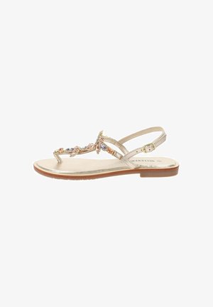 Sandal con tacco a slingback in oro, decorata con gioielli e con suola piatta. Presenta cinghie sottili e una chiusura regolabile alla caviglia.