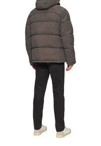 Doudoune en tissu gris foncé, avec des coutures horizontales, une capuche et une coupe décontractée, associée à un jean noir et des baskets crème.