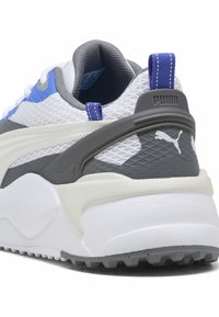 Λευκό και γκρι τακούνι αθλητικού παπουτσιού Puma με μπλε ταινία έλξης, επάνω μέρος από δίχτυ, υφή στη σόλα και το λογότυπο της Puma στο πίσω μέρος.