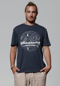 T-shirt en coton bleu marine avec un graphique circulaire blanc représentant des montagnes, des arbres et une lune, doté d'une coupe décontractée et de manches courtes.