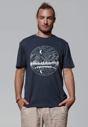 Marineblauw katoenen T-shirt met een ronde witte afbeelding van bergen, bomen en een maan, met een ontspannen pasvorm en korte mouwen.
