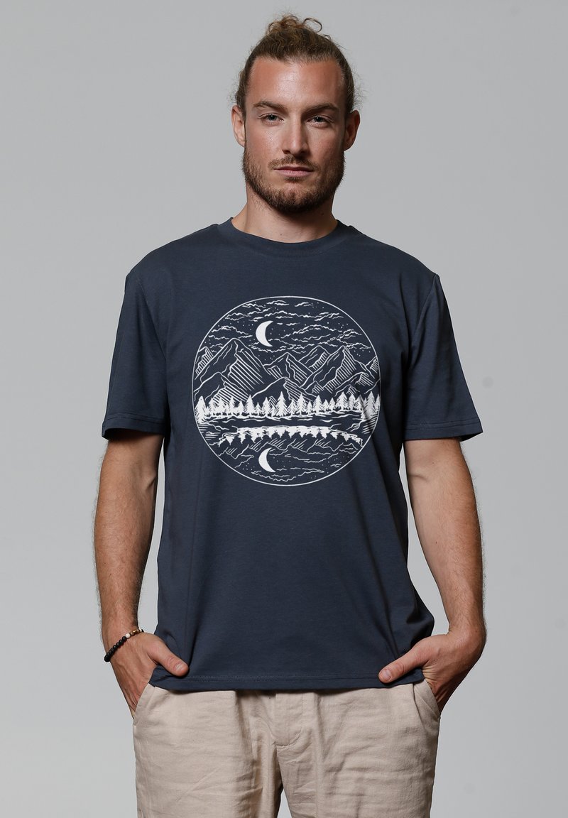 T-shirt en coton bleu marine avec un graphique circulaire blanc représentant des montagnes, des arbres et une lune, doté d'une coupe décontractée et de manches courtes.