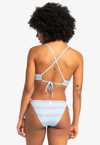 Bikini s světle modrou základnou, zdobený růžovými a bílými vodorovnými pruhy a tribal vzory. Nastavitelná šňůrka na zadní straně.