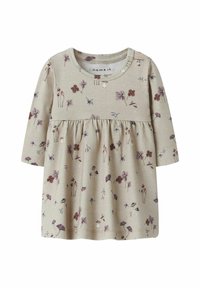 Ljus beige långärmad topp med rynkad midja, med ett blommönster i nyanser av lila, vinröd och grön. Mjuk bomullstyg.