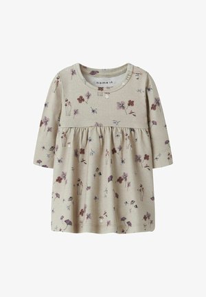 Vaaleanbeige pitkähihainen paita, jossa on gathered vyötärö ja kukkakuosi purppuran, maroonin ja vihreän sävyissä. Pehmeä puuvillakangas.