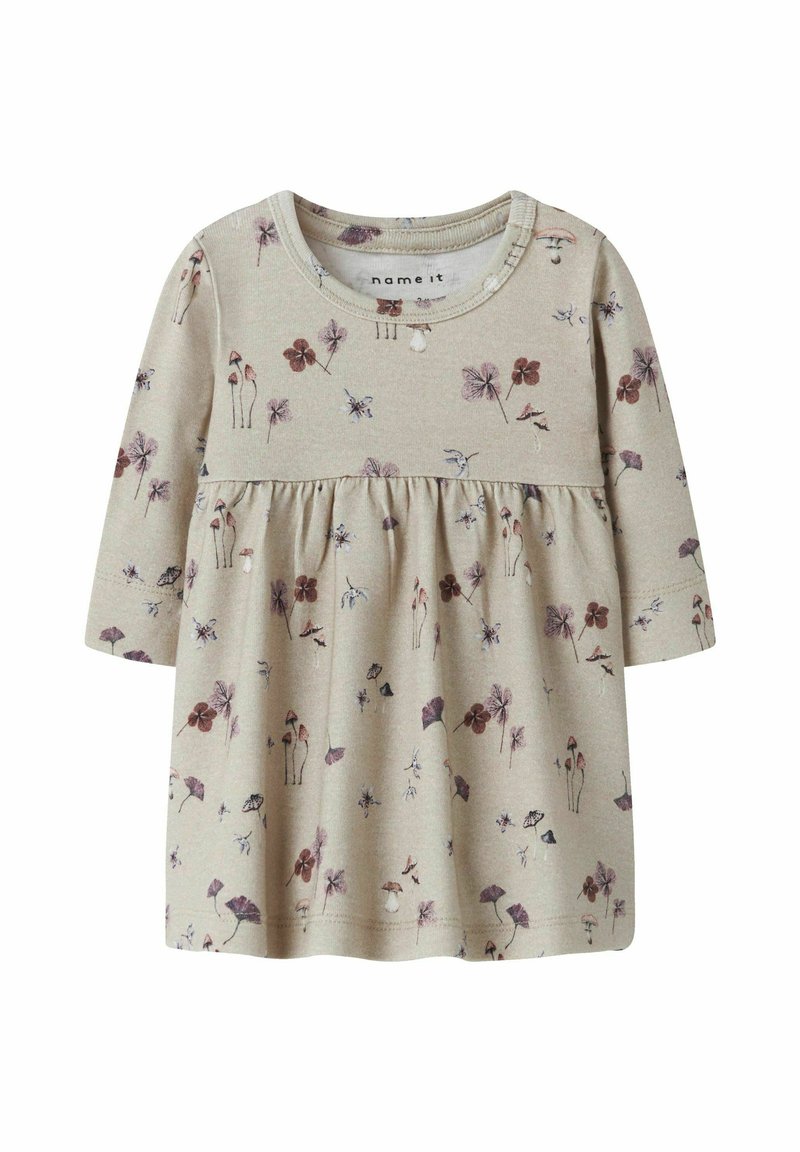 Ljus beige långärmad topp med rynkad midja, med ett blommönster i nyanser av lila, vinröd och grön. Mjuk bomullstyg.