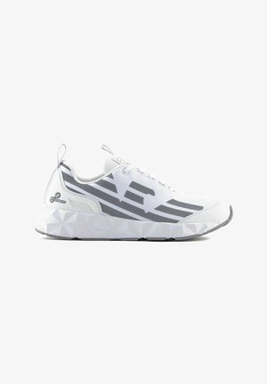 Scarpa da ginnastica bianca con suola spessa e geometrica, strisce grigie angolari ai lati e linguette di sollevamento su tallone e lingua.