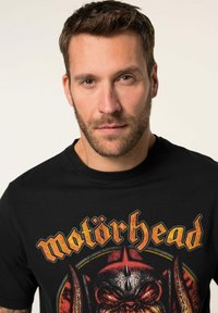 Sort bomulds T-shirt med et farverigt Motörhead-graphic og kraftige gule og røde accenter. Klassisk crew neck-design med korte ærmer.