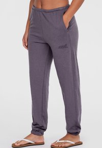 Pantaloni felpati viola realizzati in un tessuto morbido, con vita elasticizzata, caviglie elastiche e tasche laterali; con un discreto logo ricamato.