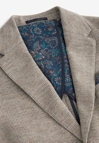 Braun kariertes Blazer mit einem blauen, gemusterten Futter mit floralen Designs. Auffällige strukturierte Revers und texturiertem Stoff.
