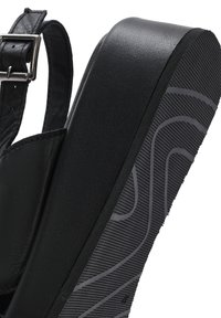 Sandalo con piattaforma nera caratterizzato da una parte superiore in pelle elegante, fibbia regolabile e suola in gomma testurizzata con un motivo ondulato.