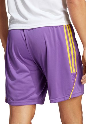 Shorts sportivi viola realizzati in tessuto liscio, con strisce laterali gialle e dettagli testurizzati sul lato in basso a sinistra.