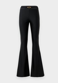 Black flared pants with a smooth texture, featuring a fitted waist and a gold circular accent in the front. Made from stretchy material.