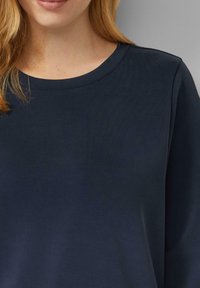 Felpa blu navy scura con scollo tondo, texture morbida e maniche lunghe. Presenta una superficie del tessuto liscia e uniforme, senza motivi o dettagli visibili.