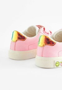 Baskets en suède rose avec des accents irisés sur le talon, semelle en caoutchouc blanc texturé et graphiques de fruits joyeux et de visages souriants sur le côté.